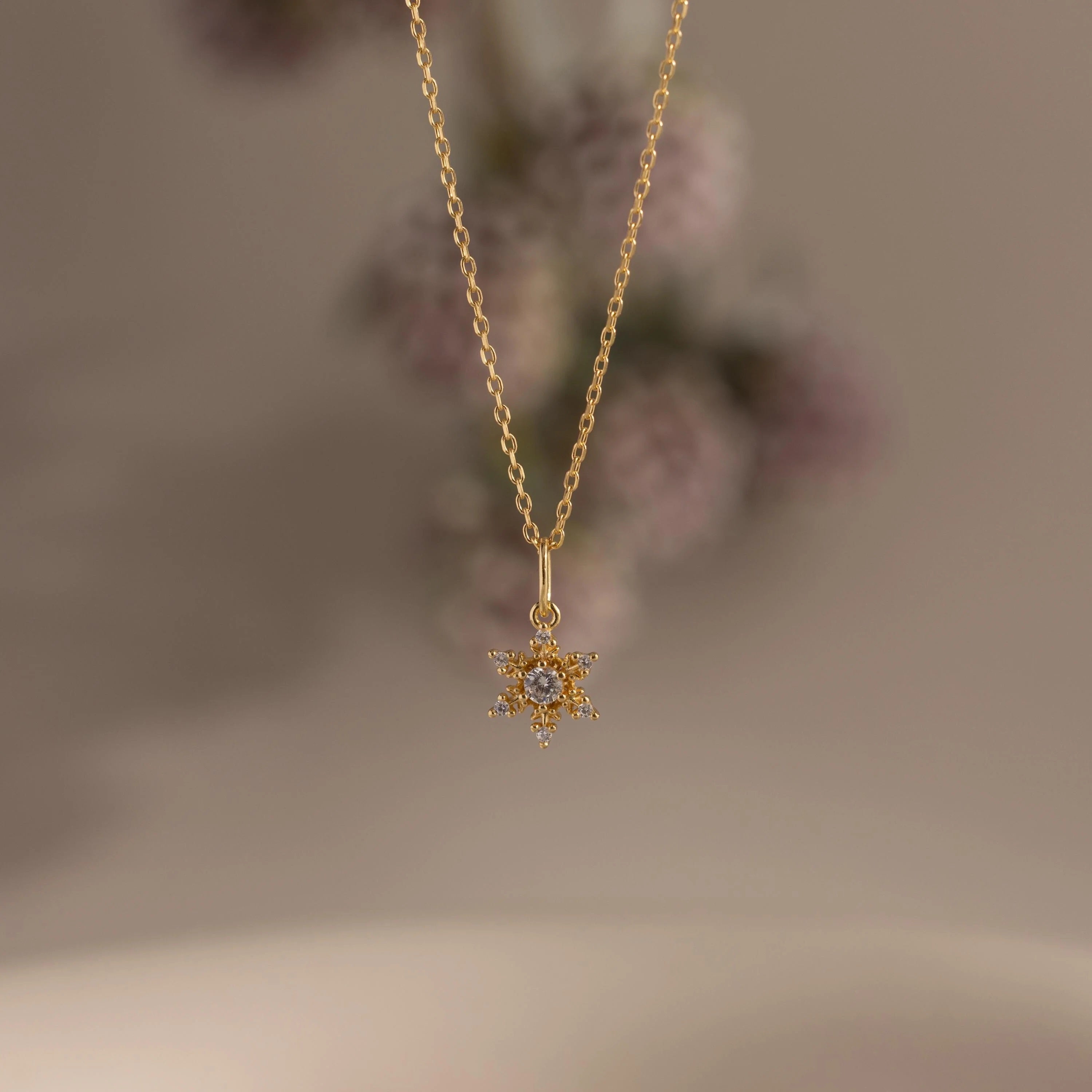 Gold necklace with a star-shaped pendant on a blurred background