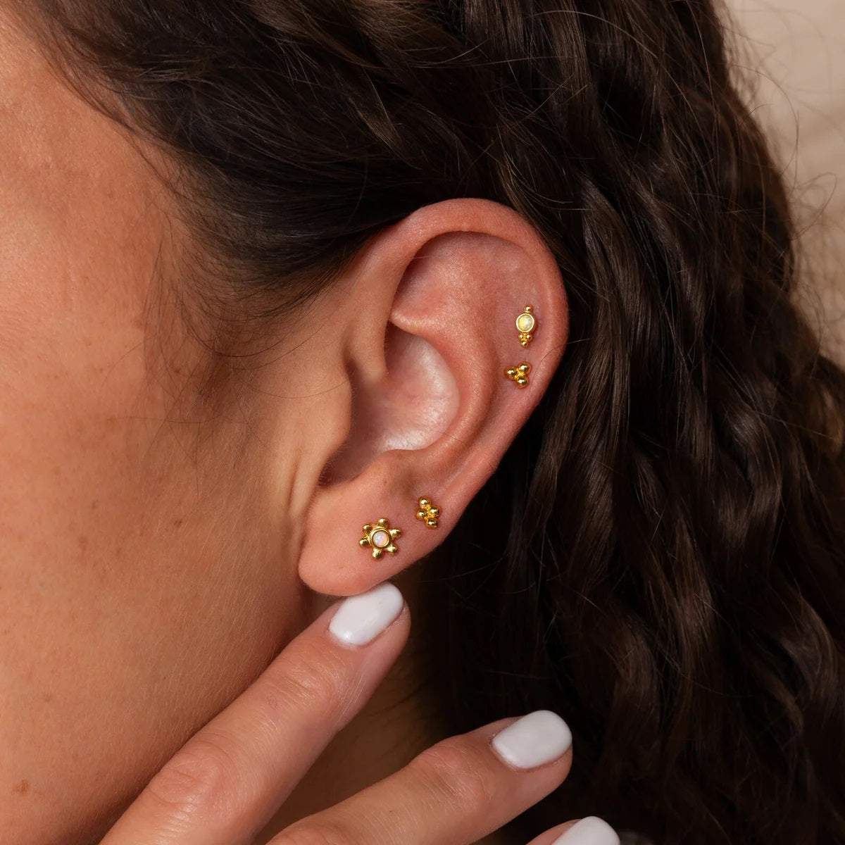 Close-up of an ear wearing gold earrings with a blurred background