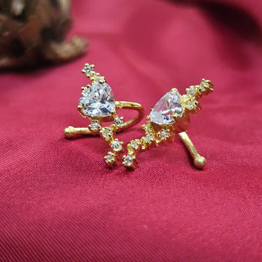 Gold earrings with heart-shaped gemstones on a red fabric background