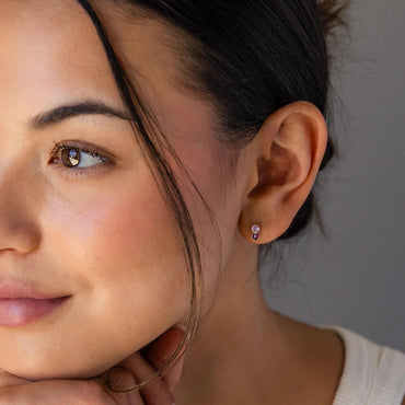 Close-up of a woman wearing a heart-shaped earring with a neutral background