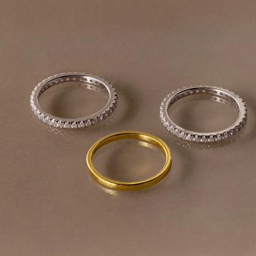 Three rings, two silver and one gold, on a brown background
