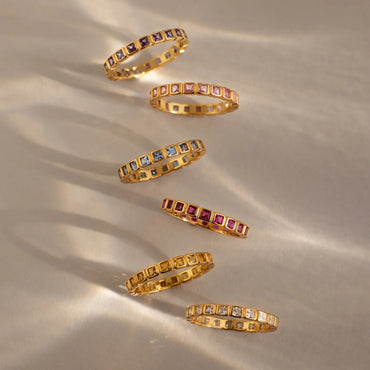 Set of gold rings with gemstones on a beige fabric background