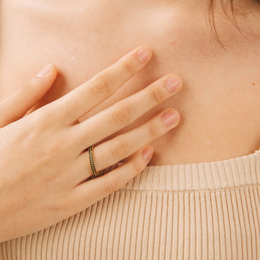 A close-up image of a hand wearing a silver and amber gemstone ring on the finger, with the rest of the hand and arm visible in a beige sweater.