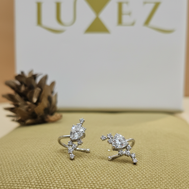 Pair of silver earrings on a textured surface with 'LuxeEZ' branding in the background.