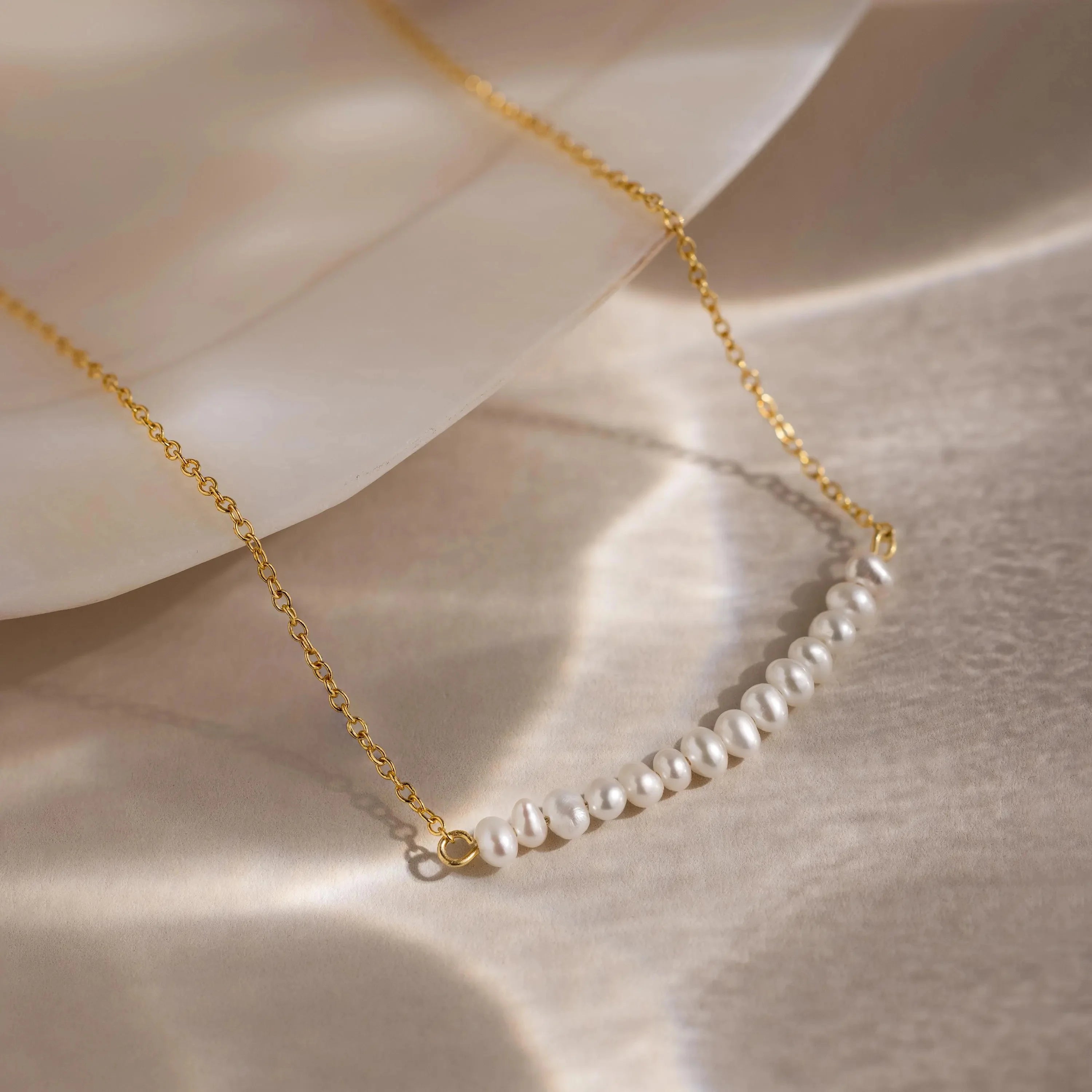 Stylish pearl curve necklace featuring round white pearls set along a gentle curved chain.