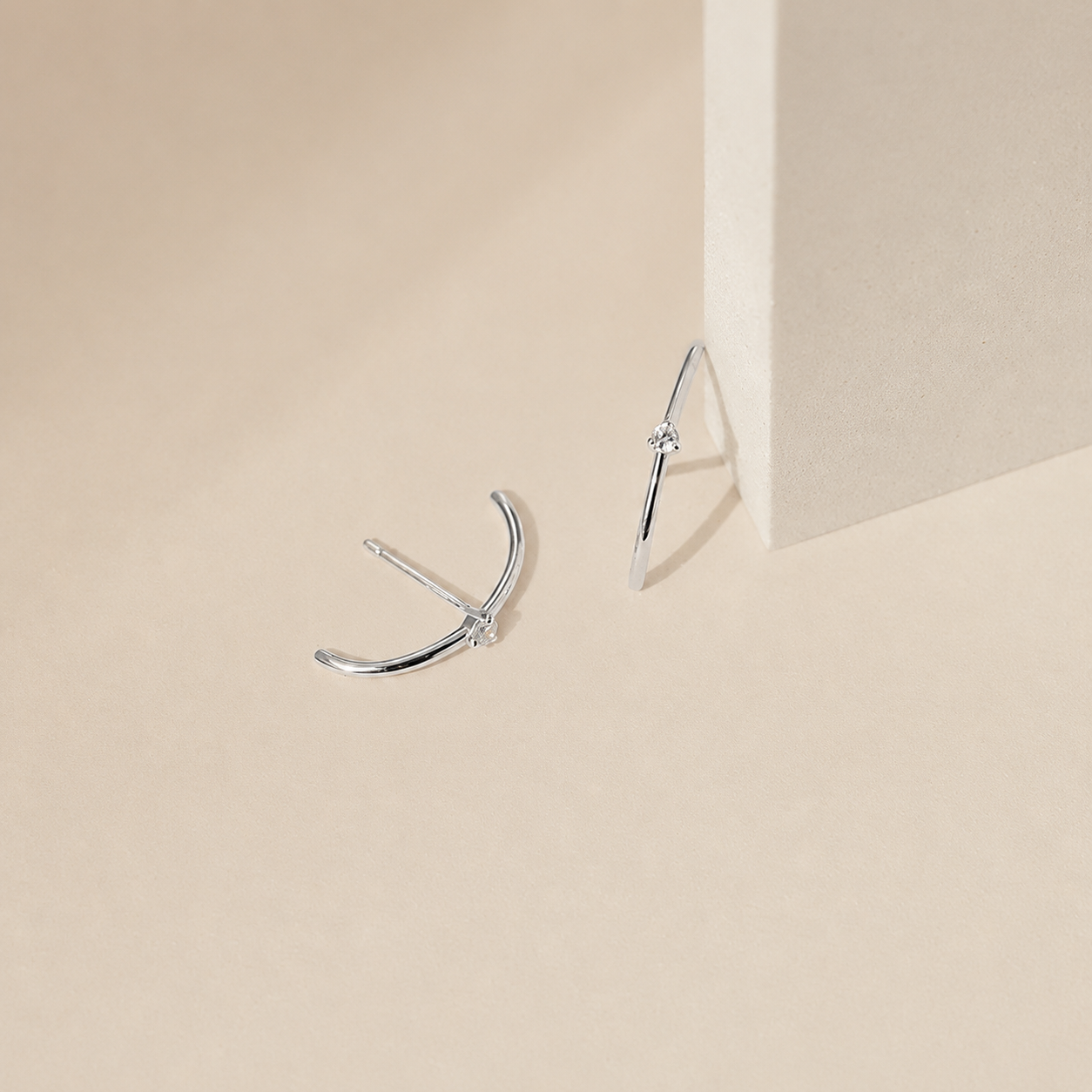 Silver earrings on a beige background