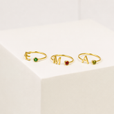 Three gold rings with gemstones on a light background