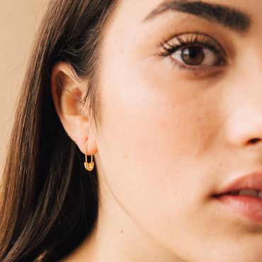 A close-up image of a woman's face, focusing on theava minimalist safety pin earrings she is wearing.