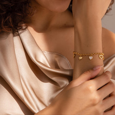 Delicate gold charm bracelet with mini heart pendants, designed by Luxez Jewels.