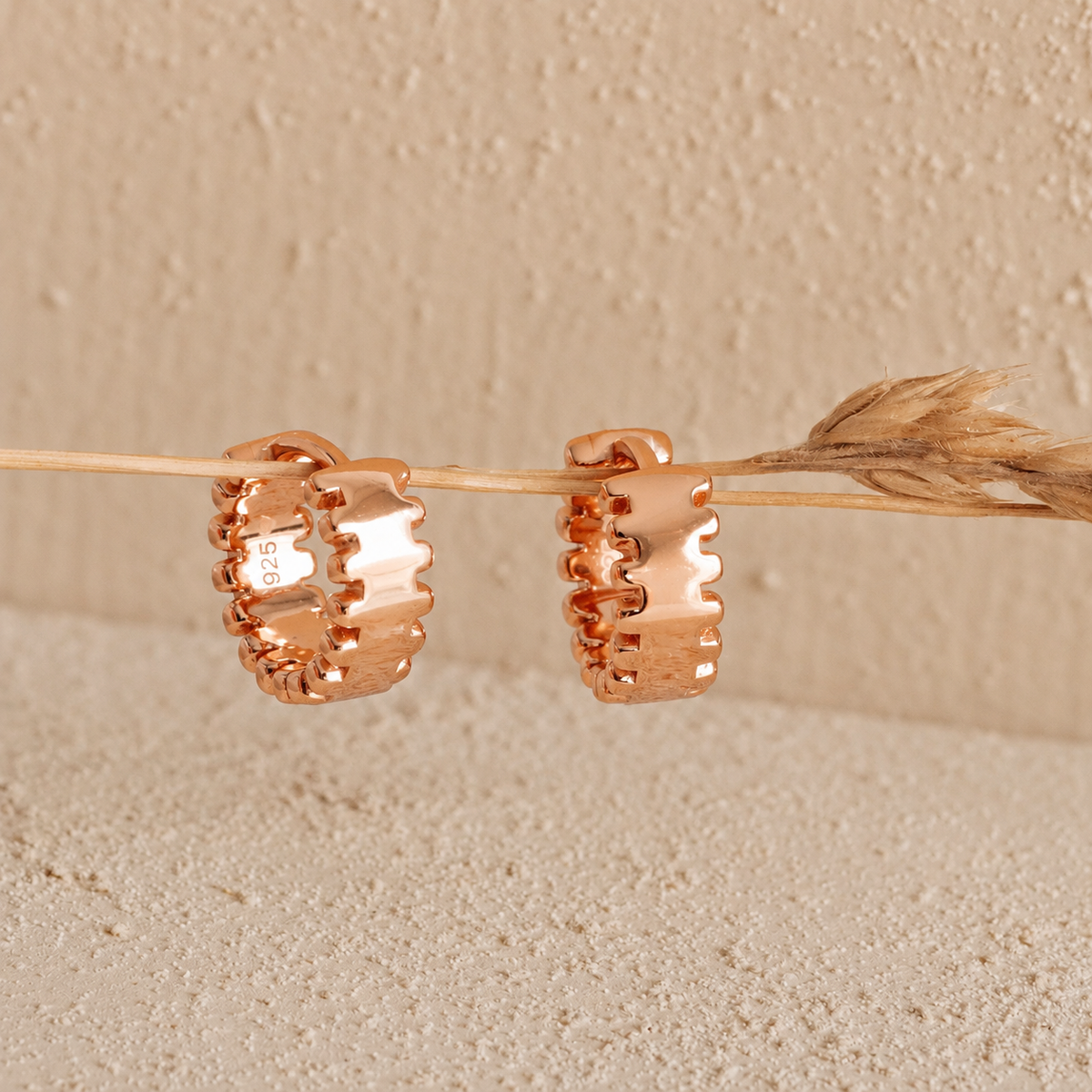 Rose gold hoop earrings on a beige background