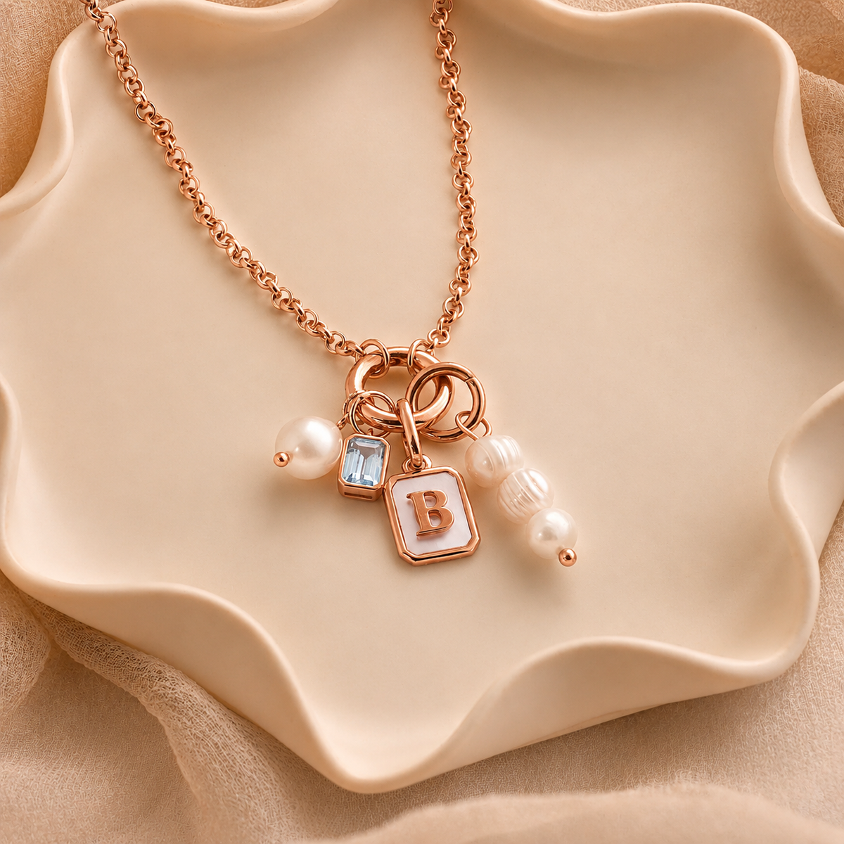 Rose gold necklace with charms on a beige dish