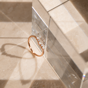 Rose gold ring with small stones on a clear crystal block