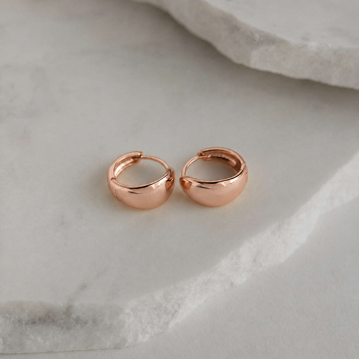 Rose gold hoop earrings on a marble surface