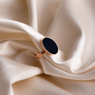 Gold ring with a black stone on beige fabric