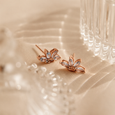 Rose gold earrings with gemstones on a beige fabric background