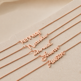 Rose gold name necklaces on a beige background