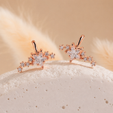 Rose gold earrings with star designs on a textured surface with a soft background