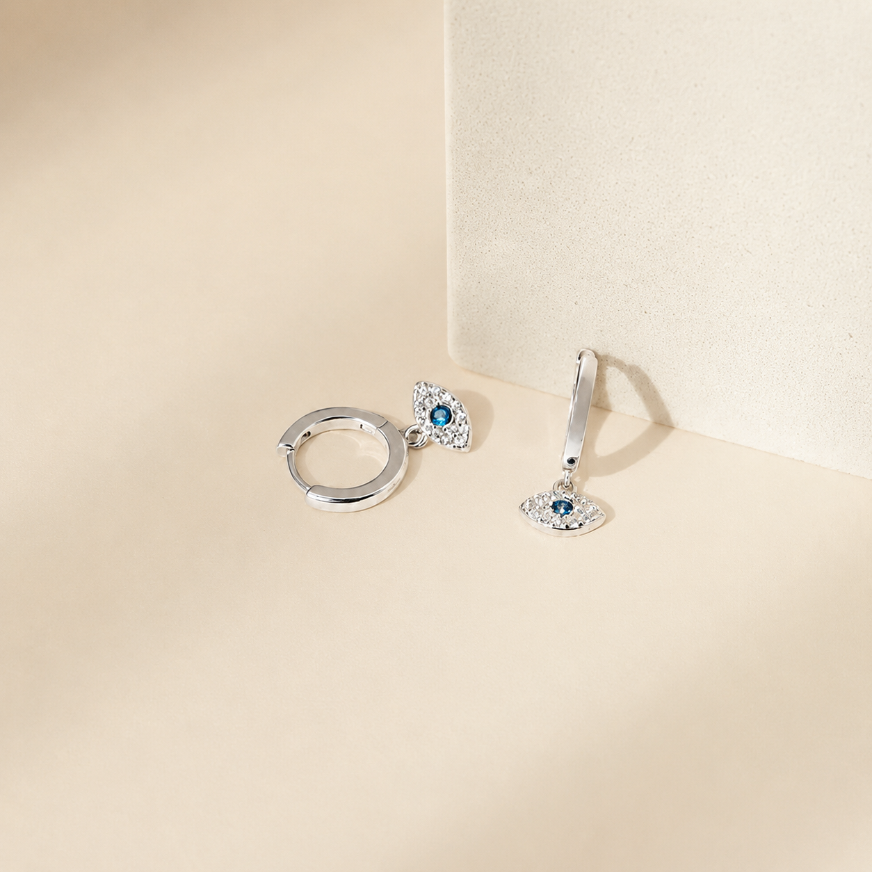 Pair of silver earrings with gemstones on a beige background