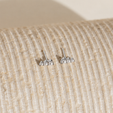 Pair of silver stud earrings on a textured beige surface