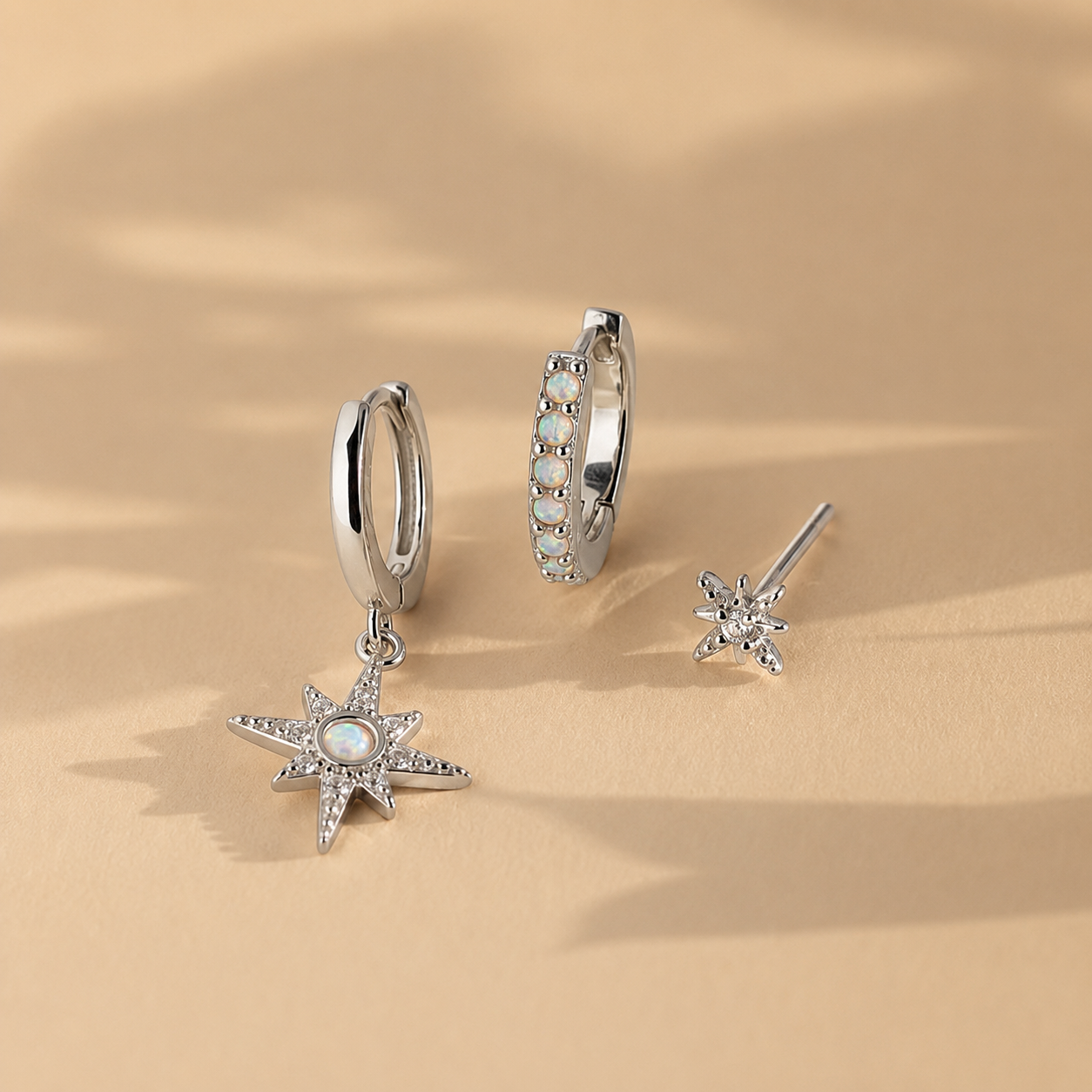 Silver star-shaped earrings on a beige background