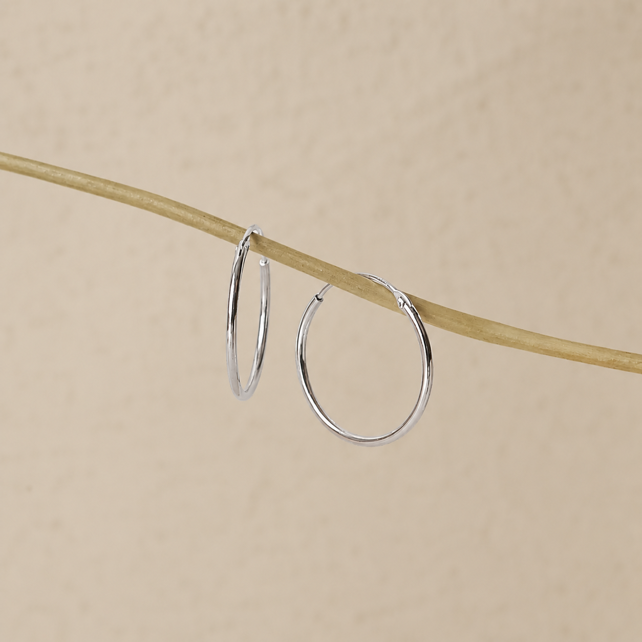 Silver hoop earrings on a beige background