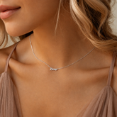 Close-up of a woman wearing a silver necklace with 'Demi' pendant.