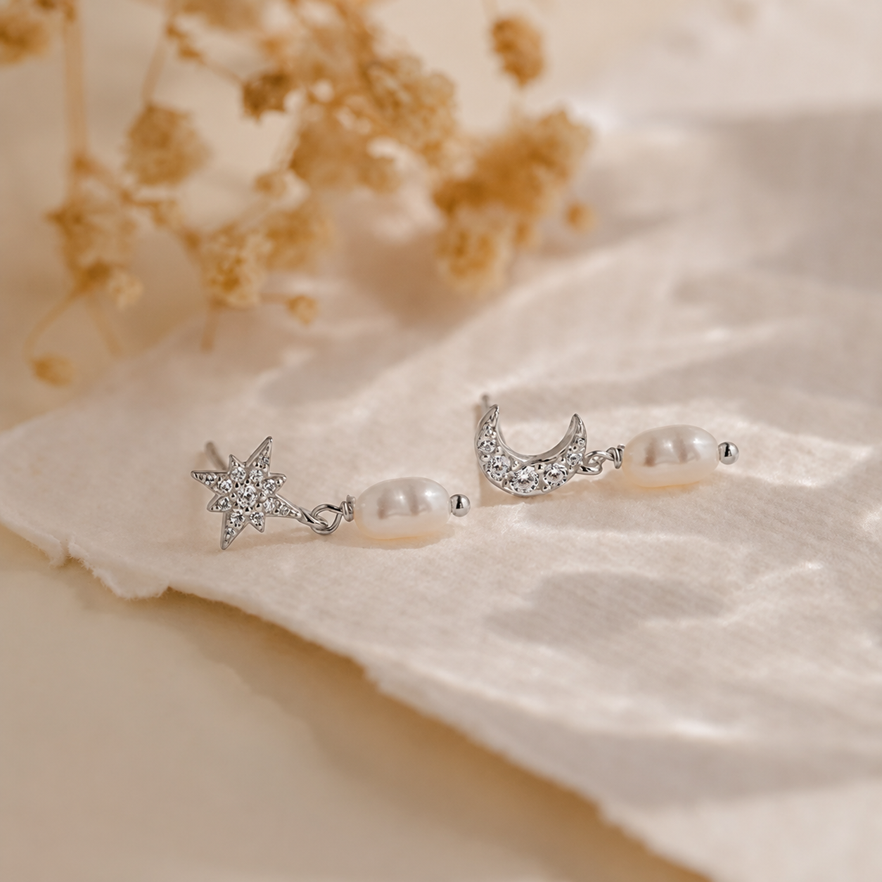 Pair of silver earrings with pearls on a soft fabric background