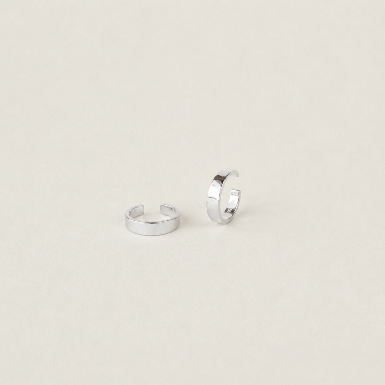 Two silver hoop earrings on a light beige background