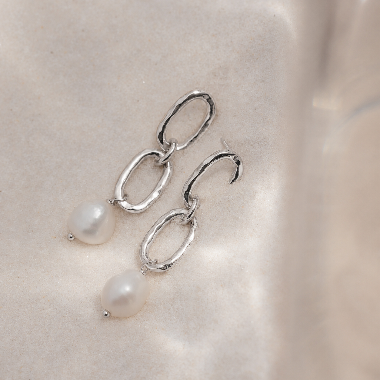Silver earrings with pearls on a light background