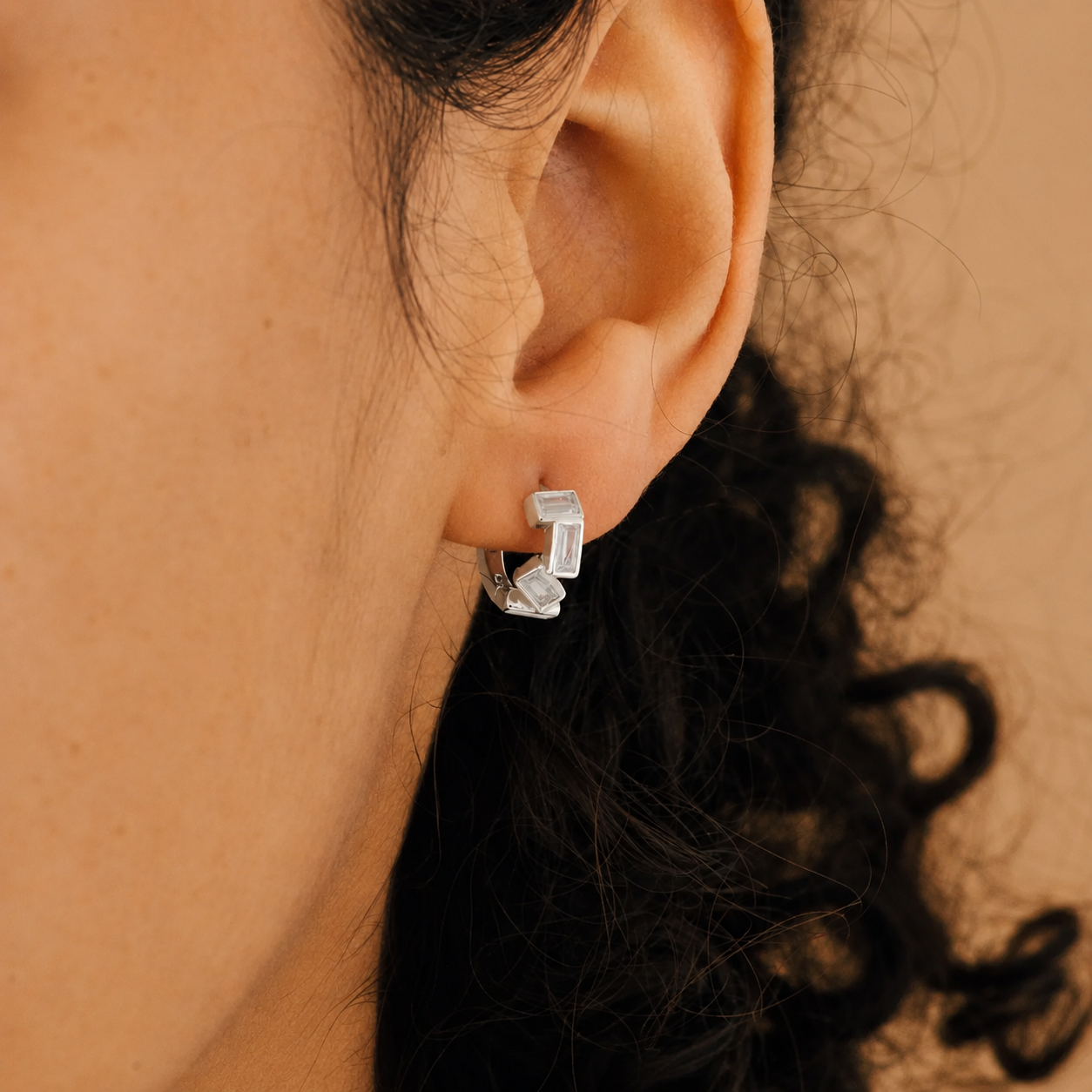 Close-up of an ear wearing a silver hoop earring with a blurred background