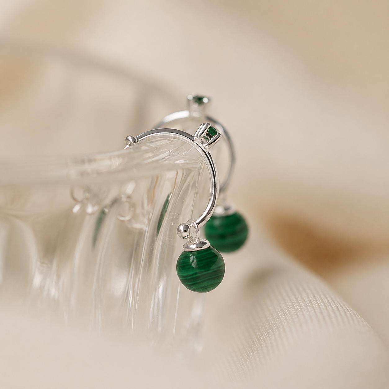 Silver earrings with green beads on a beige background