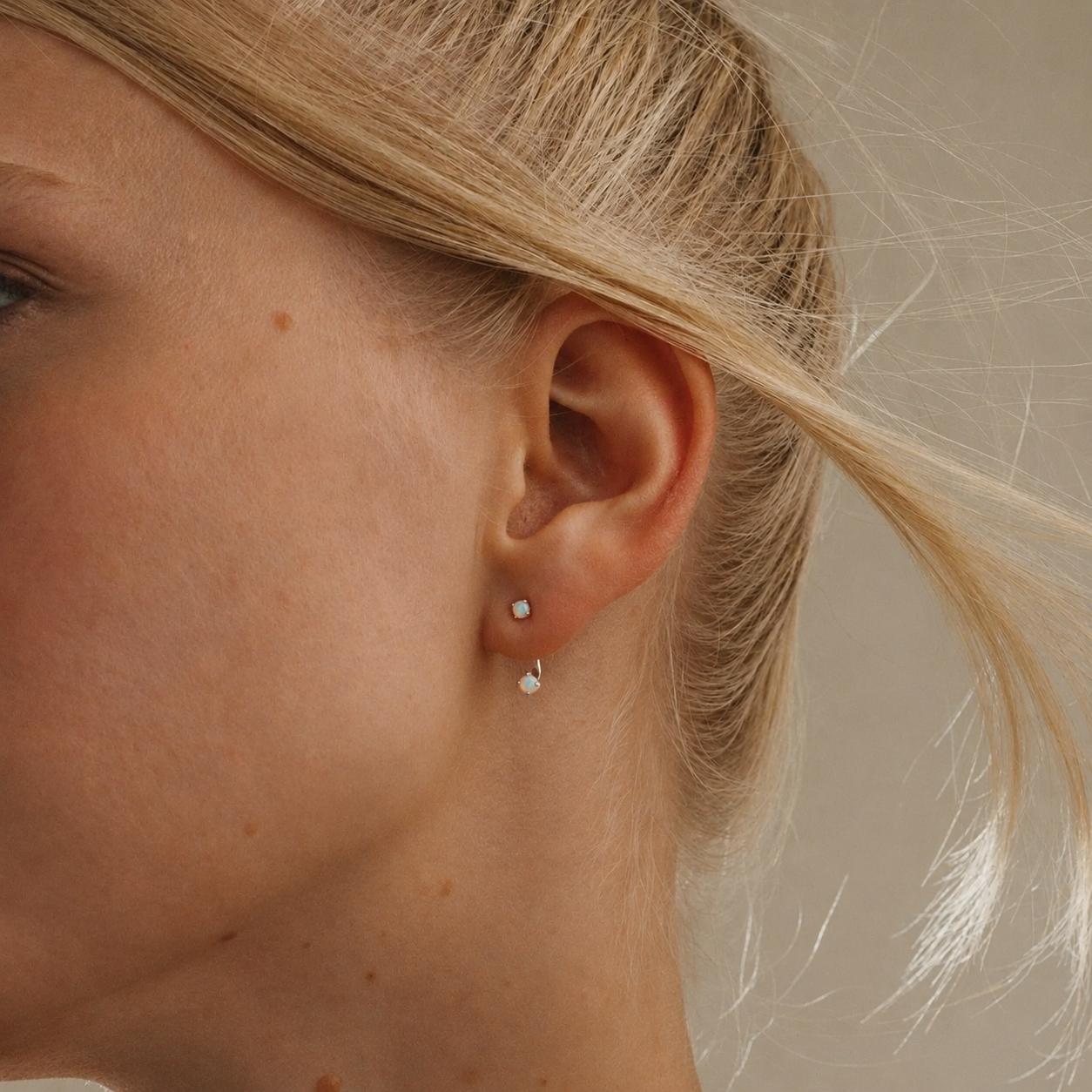 Close-up of a person wearing pearl earrings with a neutral background