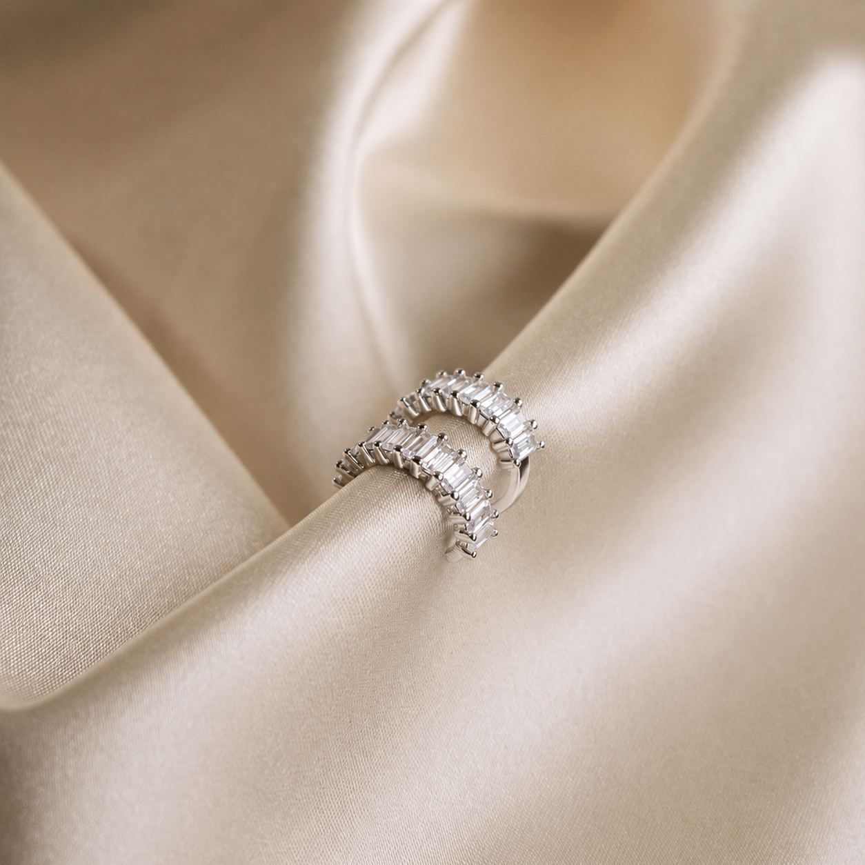 Silver ring with diamonds on a beige satin background