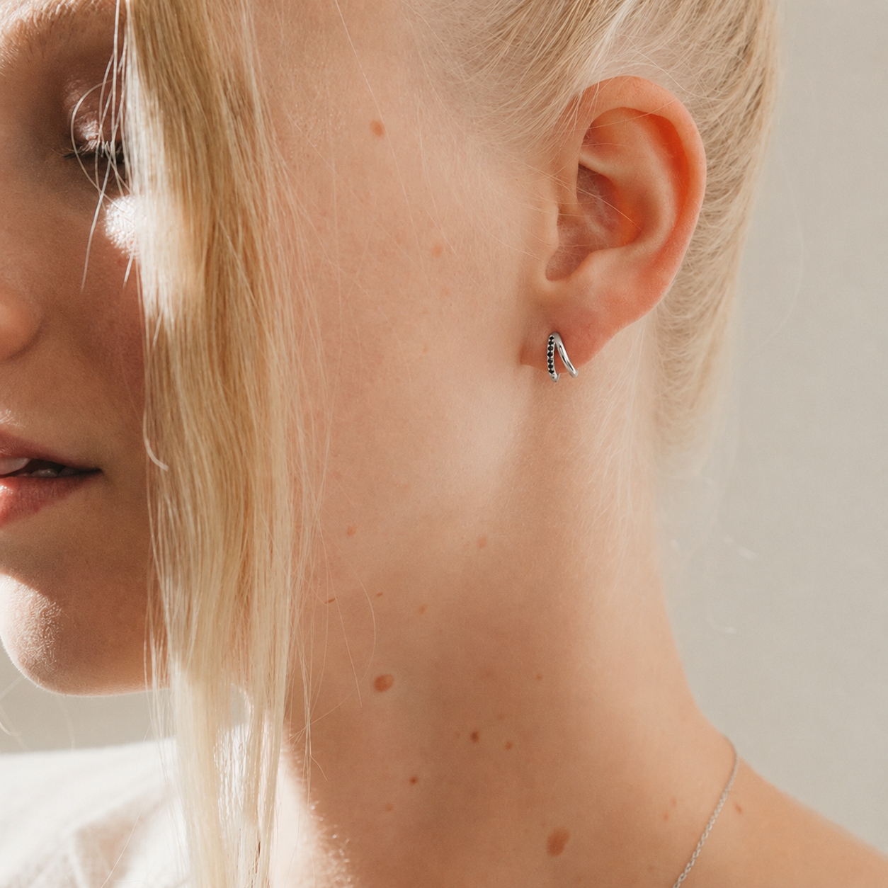 Close-up of a person wearing a small earring with a neutral background