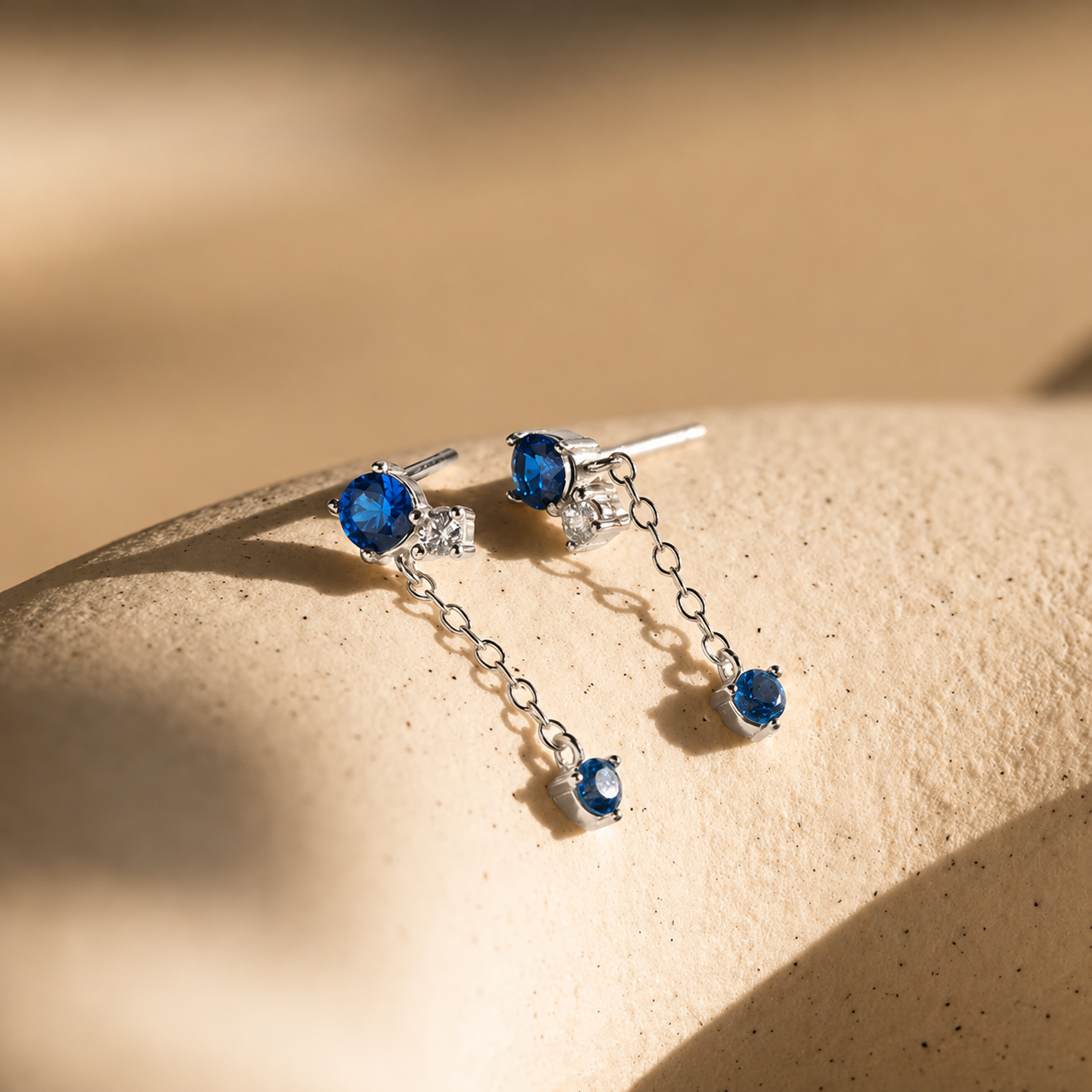 Silver earrings with blue gemstones on a beige surface