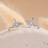 Pair of silver earrings with clear gemstones on a beige background