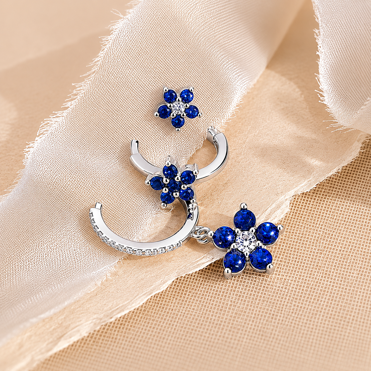 Silver earrings with blue gemstones on a beige fabric background