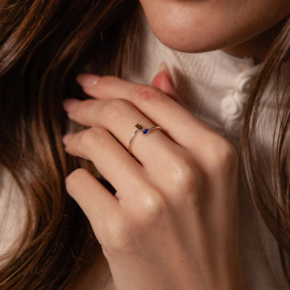 Close-up of a hand wearing a ring with a blue stone, holding hair.