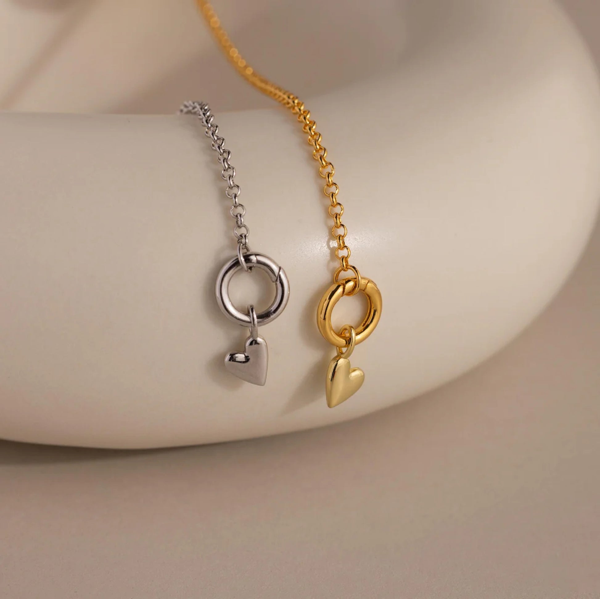 Two necklaces with heart-shaped pendants on a neutral background