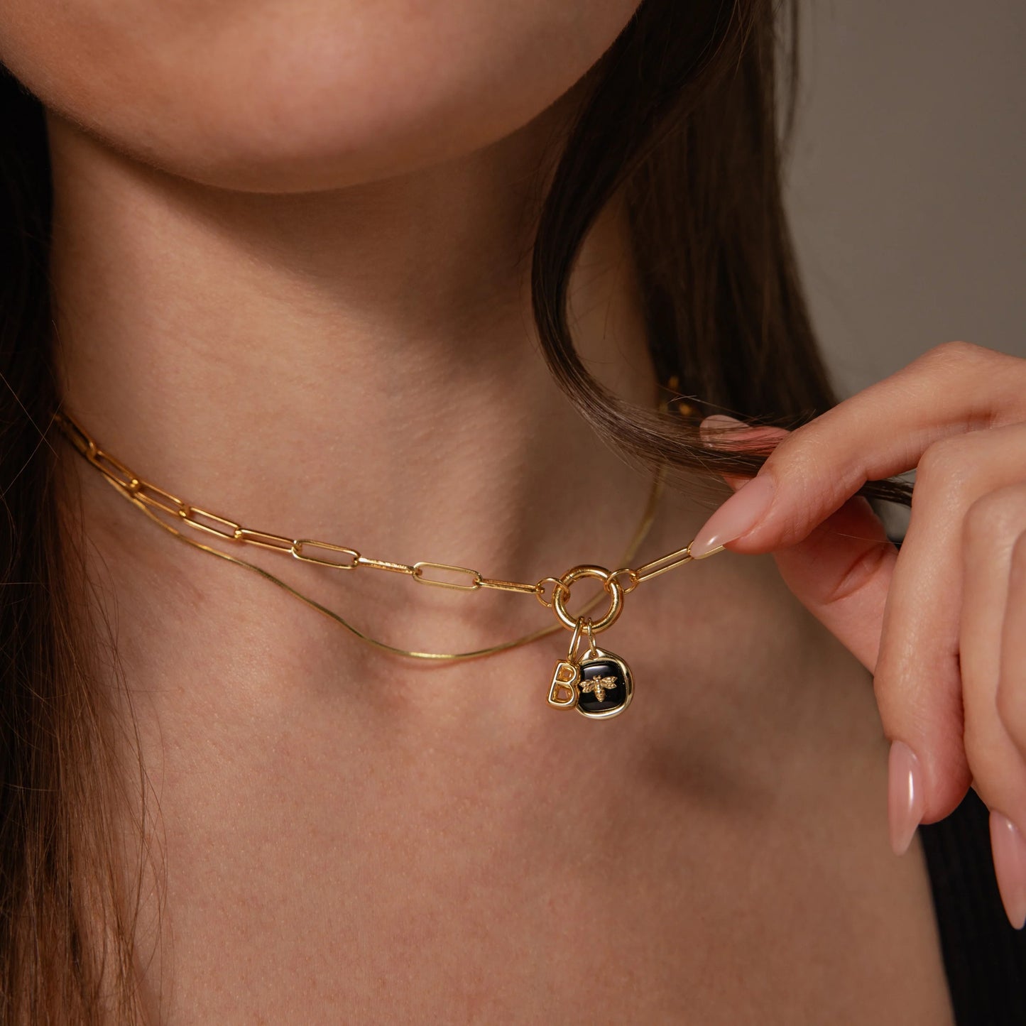 Gold necklace with a heart-shaped pendant being adjusted on a person's neck.