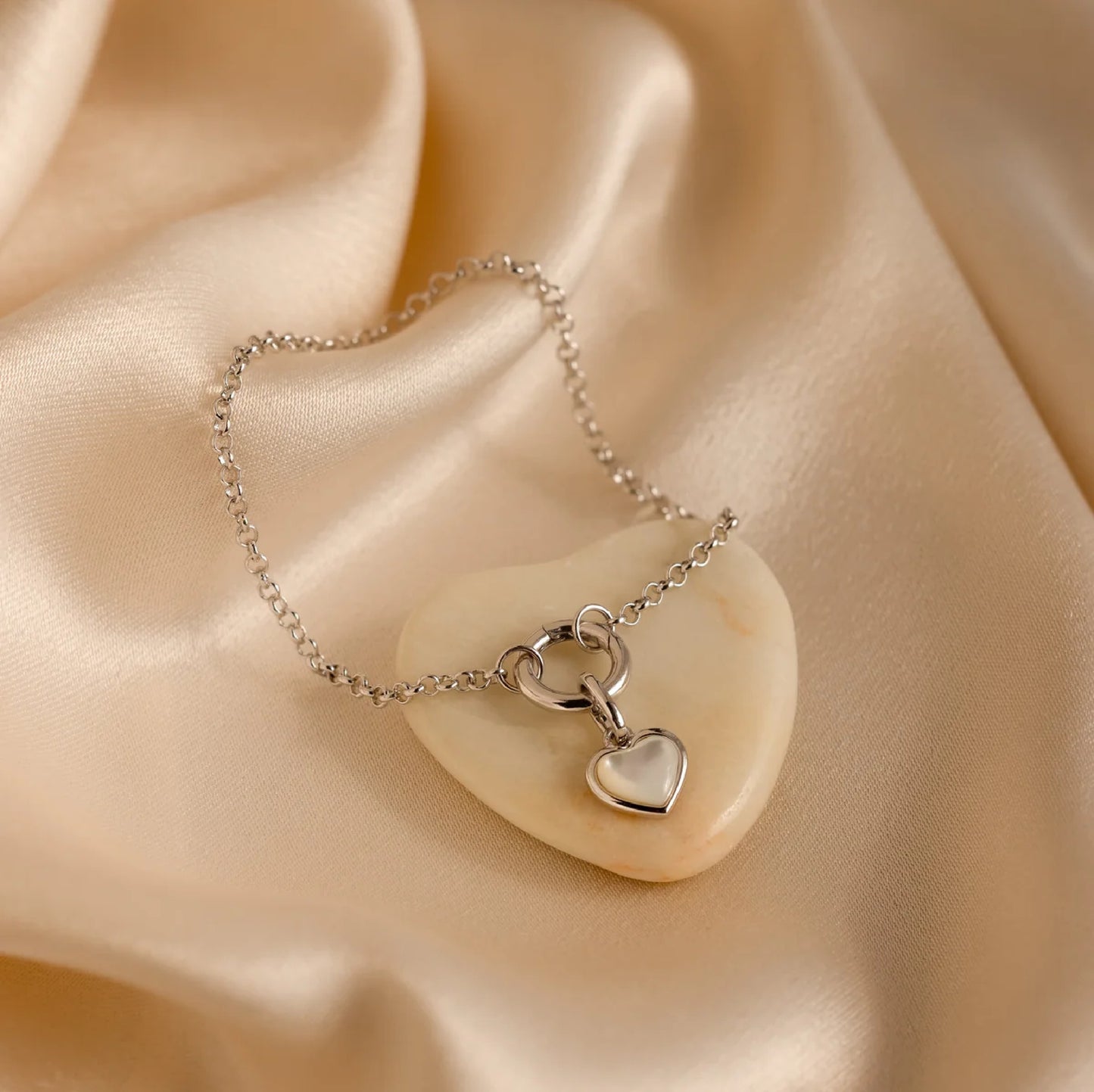 Silver necklace with a heart pendant on a beige fabric background