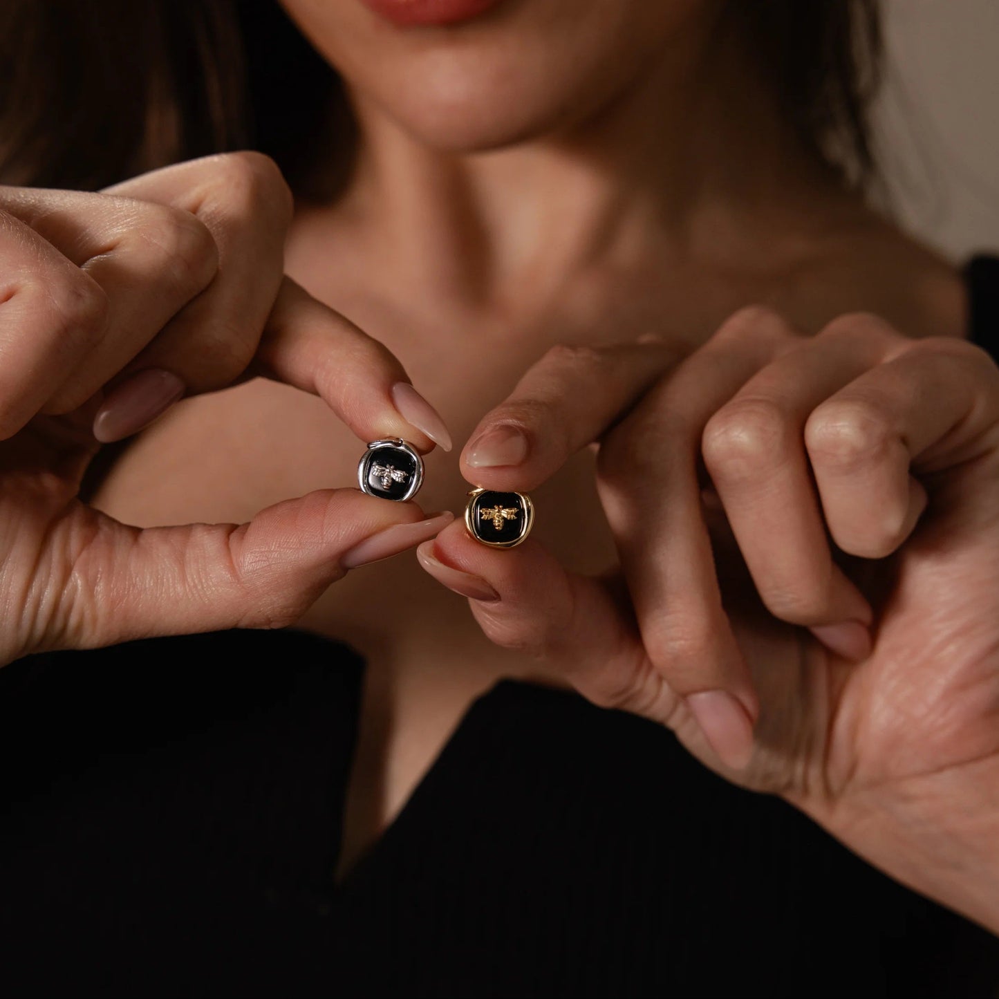 Close-up of two pairs of hands holding gold rings with gemstones.