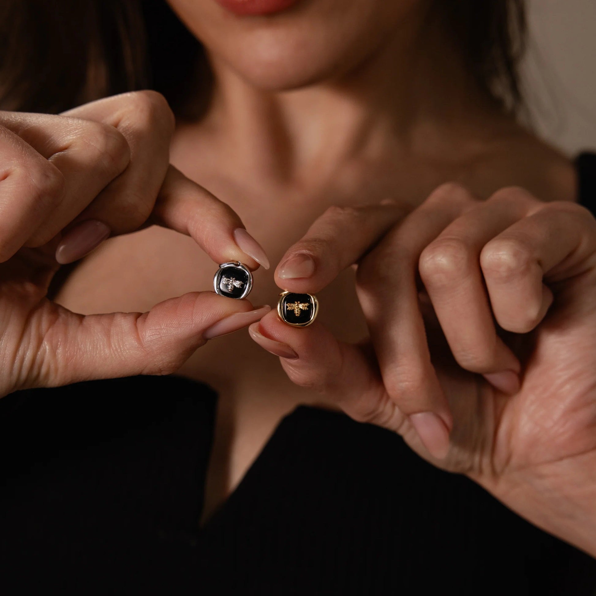 Close-up of two pairs of hands holding gold rings with gemstones.