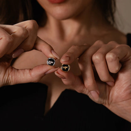 Close-up of two pairs of hands holding gold rings with gemstones.
