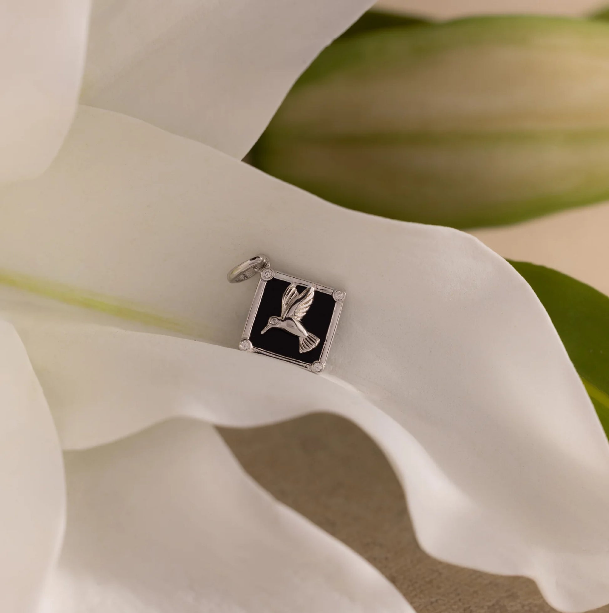 Silver pendant with a bird design on a white lily flower