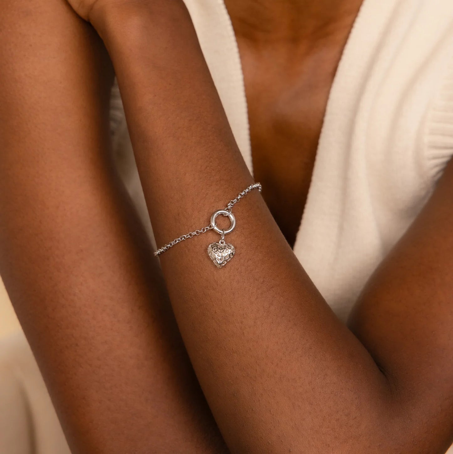 Silver bracelet with a heart charm on a person's wrist
