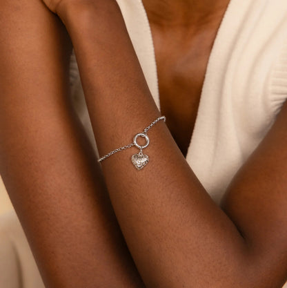 Silver bracelet with a heart charm on a person's wrist