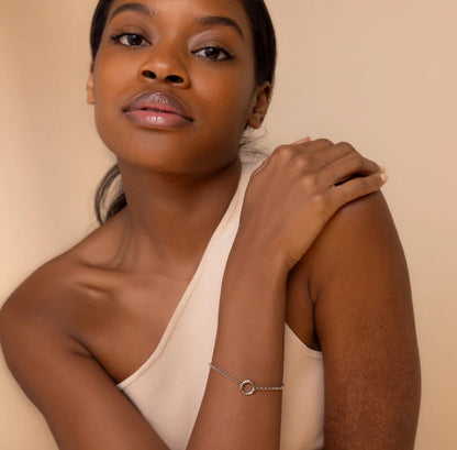 Woman wearing a beige top and silver bracelet on a beige background