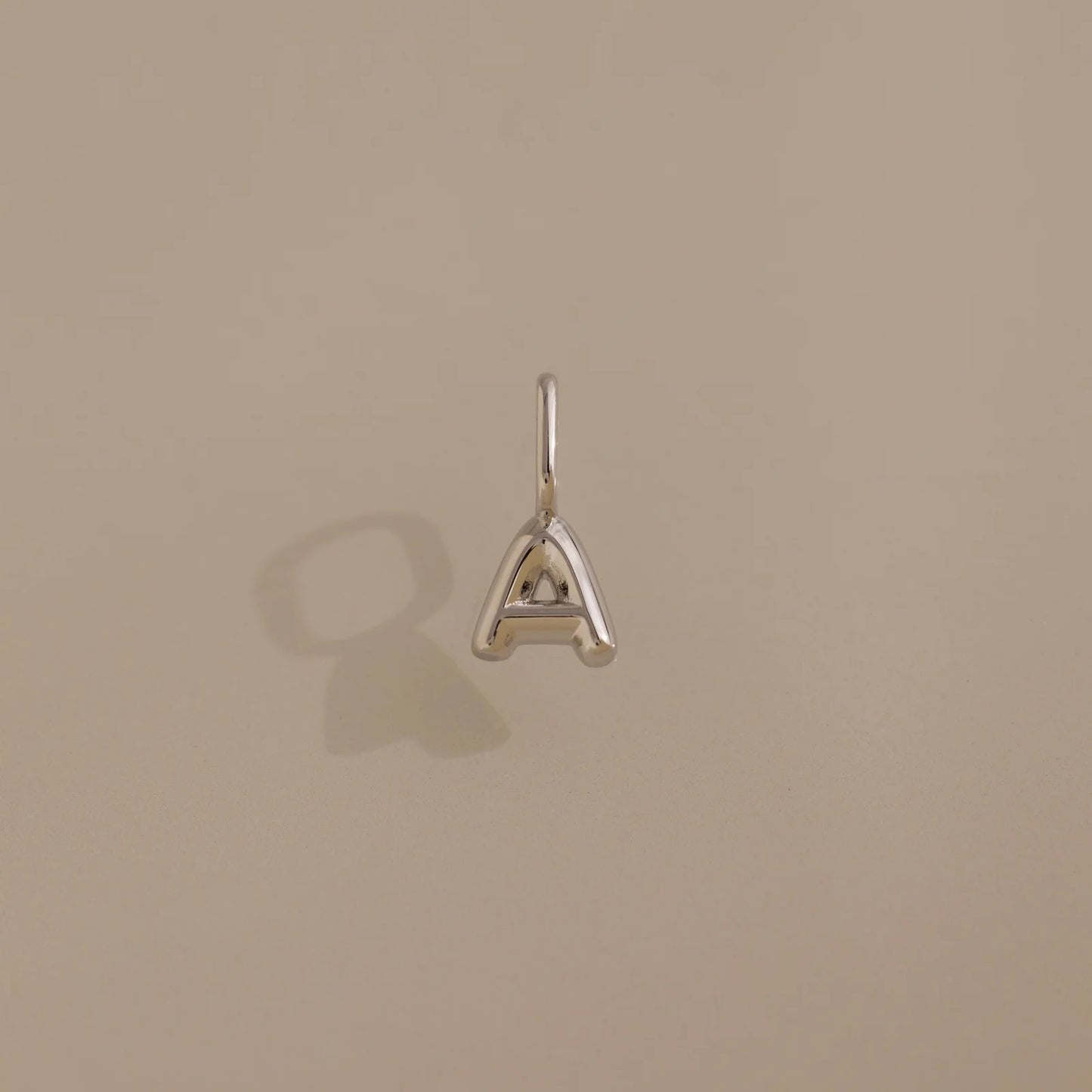 Silver 'A' letter pendant on a beige background