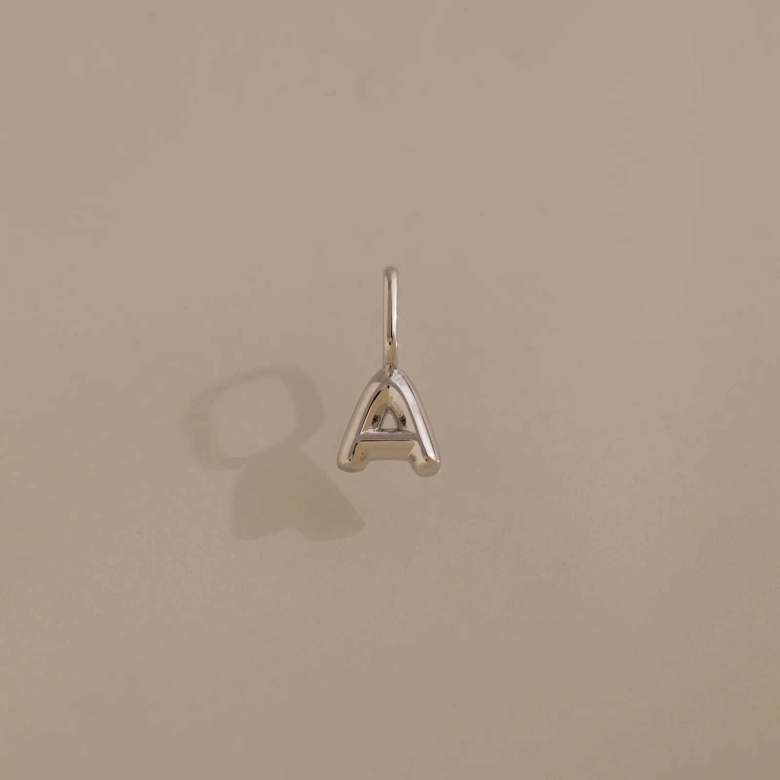 Silver 'A' letter pendant on a beige background